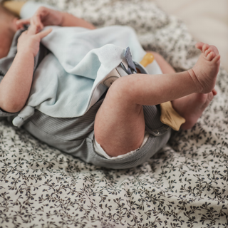 Baby lying on a floral blanket with a pacifier in mouth