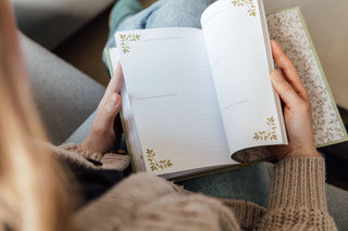 Person holding an open book with decorative pages on a couch