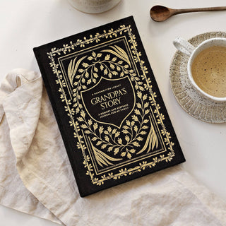 Decorative journal titled 'Grandma's Story' on a table with a cup of coffee and a spoon.