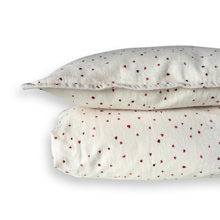 White bedding set with red heart patterns on a white background