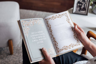 Open book with decorative text and design, held by a person.