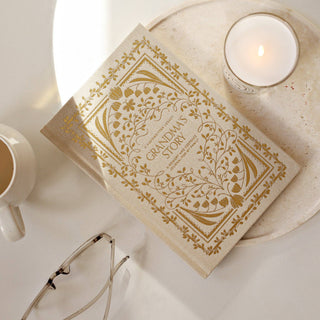 Book titled 'Grandma's Story' with a candle and glasses on a white surface
