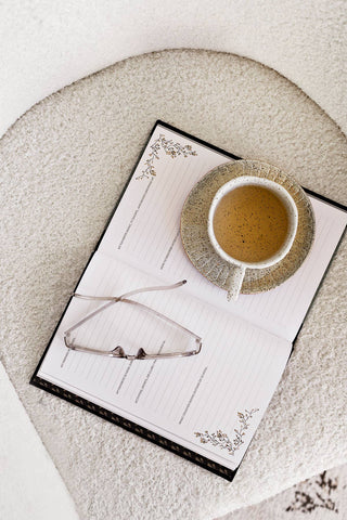 Cup of coffee on a notepad with glasses on a textured surface