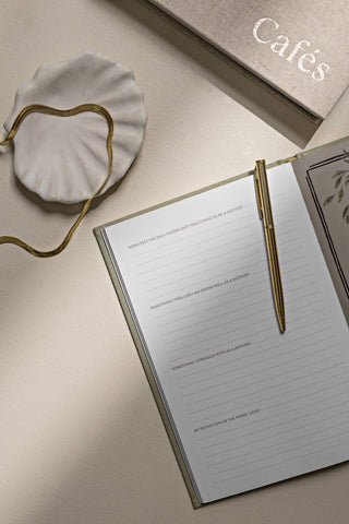 Notebook with a pen on a light surface, with 'Cafés' text in the background