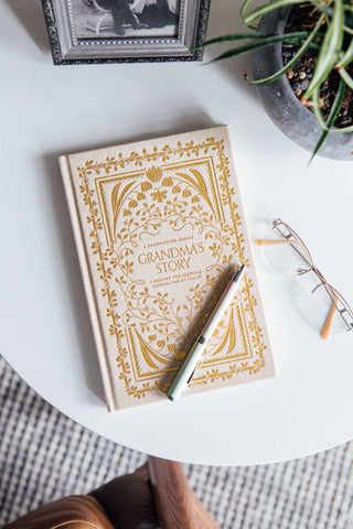 Book titled 'Grandma's Story' with decorative cover on a white surface, accompanied by a pen and glasses.